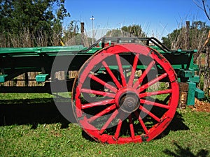RED WHEEL ON A GREEN PAINTED BED OF AN OLD OX WAGON