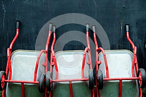 Red wheelbarrows against dark wall background