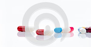 Red-white antibiotic capsule pill on blur multi-colored capsules background. Antibiotic drug resistance concept. Pharmacy