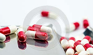 Red, white antibiotic capsules pills with shadow on stainless steel drug tray, drug resistance concept.