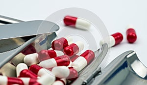 Red, white antibiotic capsules pills on stainless steel drug tray, drug resistance concept.
