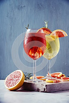 Red and white aperol spritz garnish in wine glasses with rosemary and grapefruit on luxury marble table. Bitter sparkling