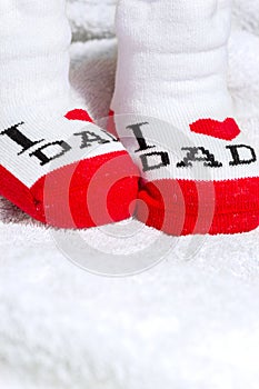 Red and white Baby socks on white blanket showing love to father text