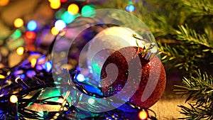 Red, White Balls, Pine Branches and Garlands of Multicolored LED Lamps Lie on a Table Close-up. Christmas Holidays and