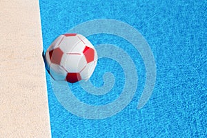 Red-white beach ball floating in swimming pool