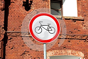 Red and white bicycle lane forbid sign indicating the end of the bike route, large round roadside traffic signage.