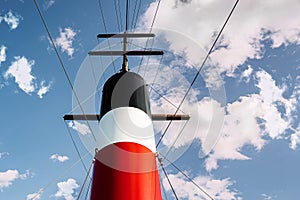 A red white and black chimney on a boat on a sunny cloudy day