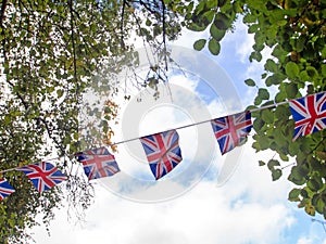 Red, white and blue festive bunting flags against sky background. Union Jack, UK flags blowing in the wind. Brexit maybe