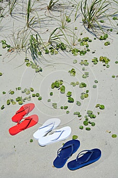 Red white and blue flip flops on the beach.