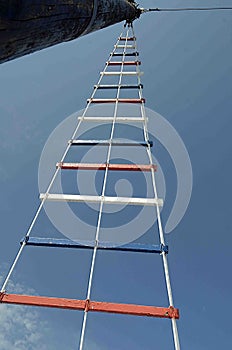 Red white and blue laddering on a sail boat on blue sky background