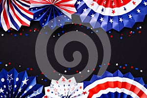 Red white and blue paper fans with confetti on black table. American patriotic birthday party decorations for USA themed event.