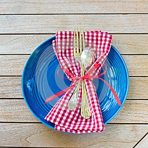 Red White and Blue Picnic Table Place Setting with napkin, fork, spoon and plate. Square and flat layout style photo taken outsid