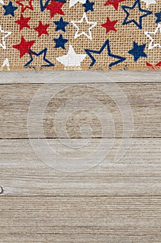 Red, white and blue stars burlap ribbon on weathered wood background