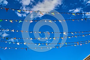 Red white and blue triangular bunting on sky background. Garland of flags stretched against a blue sky with white clouds