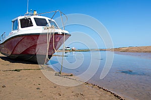 Red and white boat moored by a river