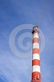 Red and white brick industrial pipe against the blue sky.2