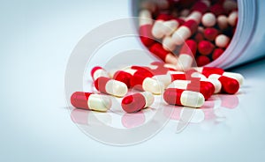 Red-white capsule pills on white table on blurred background of drug bottle. Antibiotics drug resistance. Antimicrobial capsule