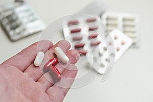 Red and white capsules with medicine on the background of different blisters with pills