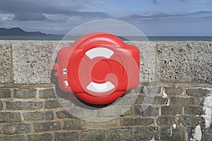 Red and white case with rescue buoy on a wall with the sea on the background