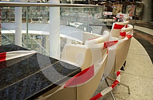 Red and white caution tape restrict dining area of restaurant or cafe inside shopping mall.