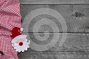 Red and white checkered fabric with santa head on wooden background