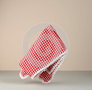 Red and white checkered kitchen towel levitates on beige gray background