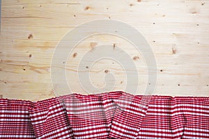 Red white checkered picnic tablecloth on wooden background, copy space