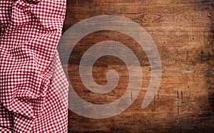 Red white checkered picnic tablecloth on wooden background, copy space