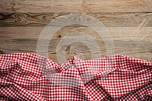 Red white checkered picnic tablecloth on wooden background, copy space photo