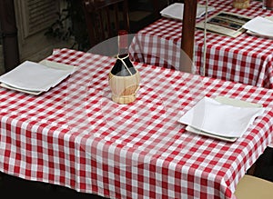 Red and white checkered tablecloths with a flask bottle of wine in the Italian trattoria
