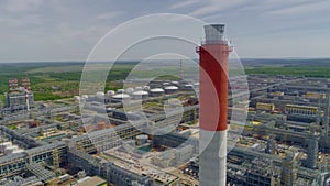 Red white chimney at refinery complex with pipes aerial view