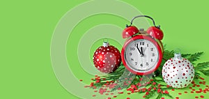 Red and white Christmas balls,  confetti, alarm clock and tree branches on green paper background. 5 minutes before the New Year