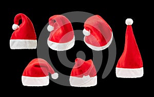 Red and white christmas hat set on black background. Santa claus cap from different angles on the plain dark background