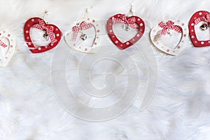 Red and white colored wooden heart shaped xmas ornaments on a soft fabric, close up, isolated