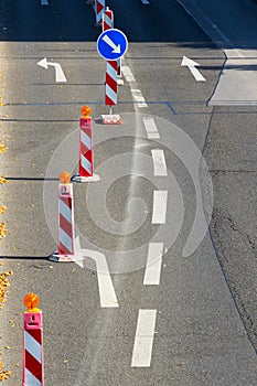 Red and white construction roadblocks with direction signs, sunny day