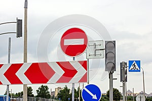 Red and white Do not enter and other signs on gray dull overcast sky background.