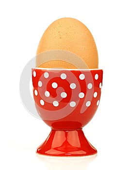 Red and white eggcup with an egg