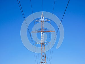 Red white electricity pylon against blue sky