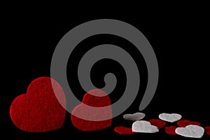 Red and white felt hearts isolated on a black background - valentines, love