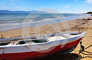 Red and white fisher boat in front of the blue beah at Kavos