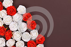 Red and white foam rose flowers at side of dark brown background with copy space