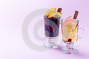 Red and white glogg or mulled wine with orange and apple slices and cinnamon stick on pink background, horizontal, copy space