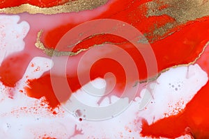 Red, white and gold paint liquid background. Abstract rich texture.