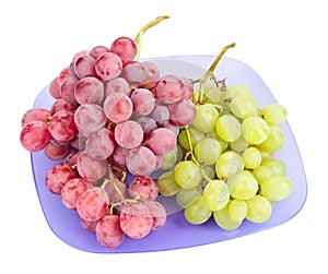 Red and white grapes bunches on blue plate