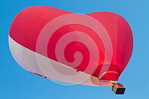 Red white heart shaped hot air balloon flying