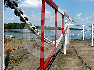 red and white with heavy chain and gate in diminishing perspective at a river side