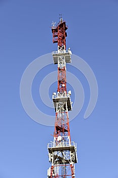 Red and White High rise communication tower Antenna in the city with transmitters