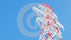 Red and white high voltage tower against clear sky