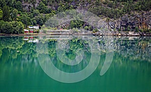 Red and white house sit on the waters edge near Skjolden, Norway