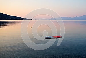 Red and White Kayak Anchored in Bay at Dawn